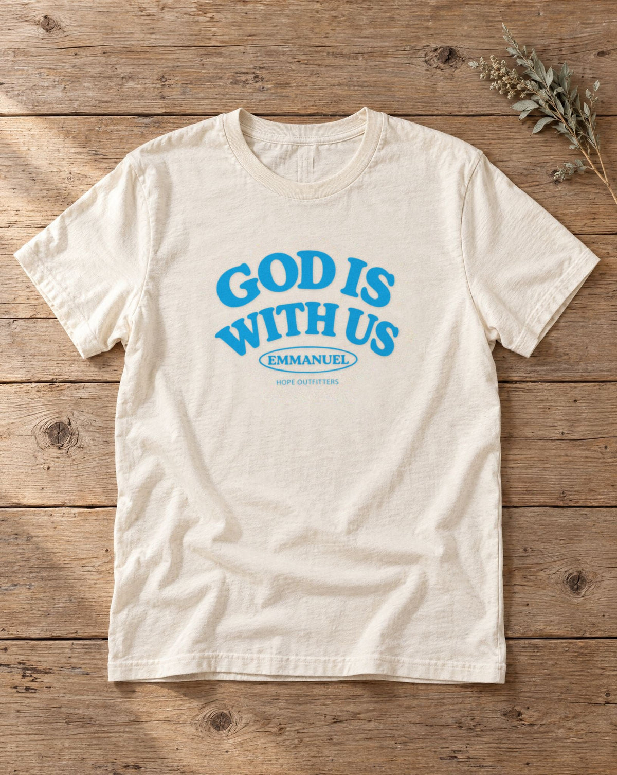 Emmanuel God Is With Us Tee - natural tee flat lay on wood showing the God Is With Us front print