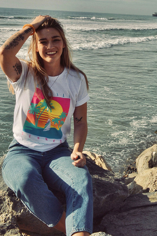 Woman by the ocean wearing the white Eternal Summer tee