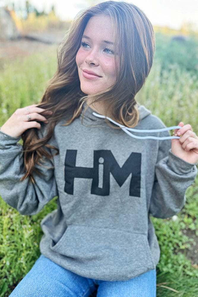 Woman wearing the gray HiM hoodie outdoors