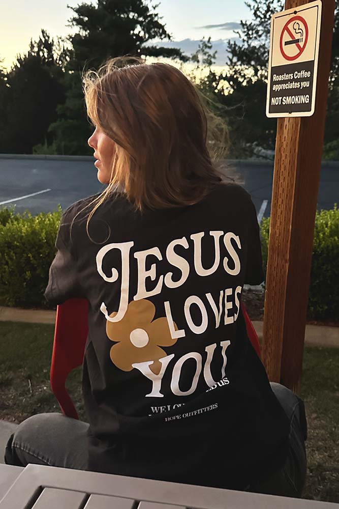 Woman wearing the black Jesus Loves You tee, back view
