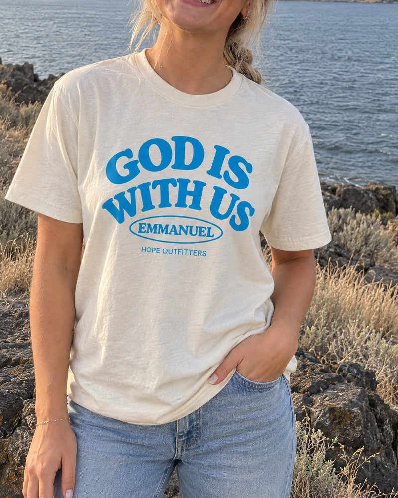 Emmanuel God With Us Tee - close-up of the natural tee's blue God Is With Us print worn by a blonde woman by the Columbia River