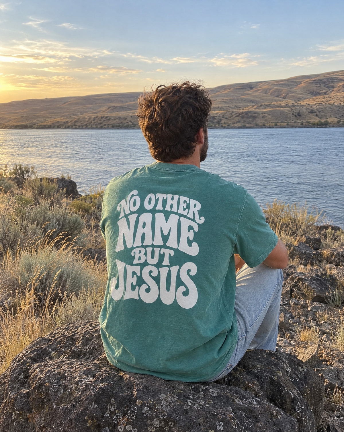 No Other Name But Jesus Tee - man sitting on a basalt boulder looking at the river, back print visible