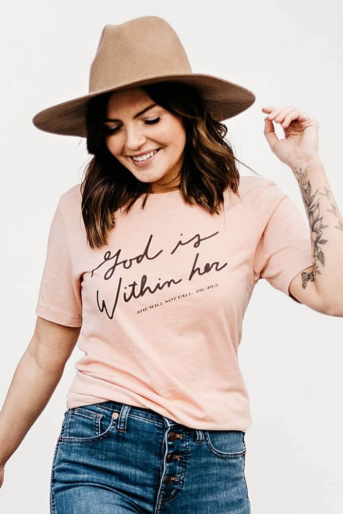 Woman in a hat wearing the peach God Within Her tee